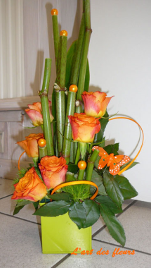 Composition avec rose orange,feuillage divers et accessoire