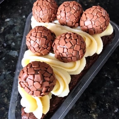 Fatia de brownie com cobertura de leite ninho e mini brigadeiro belga