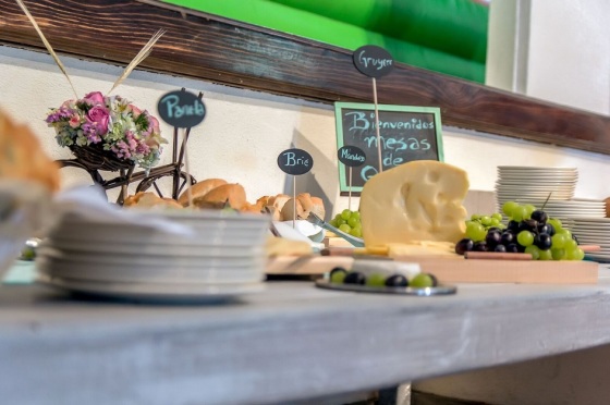 Servicio de mesa de quesos, uvas y panes artesanales.