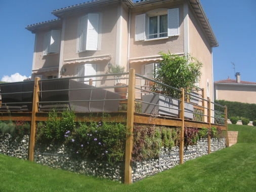 Terrasse sur pilotis en chêne avec habillage des soubassements en gabion et mur végétal